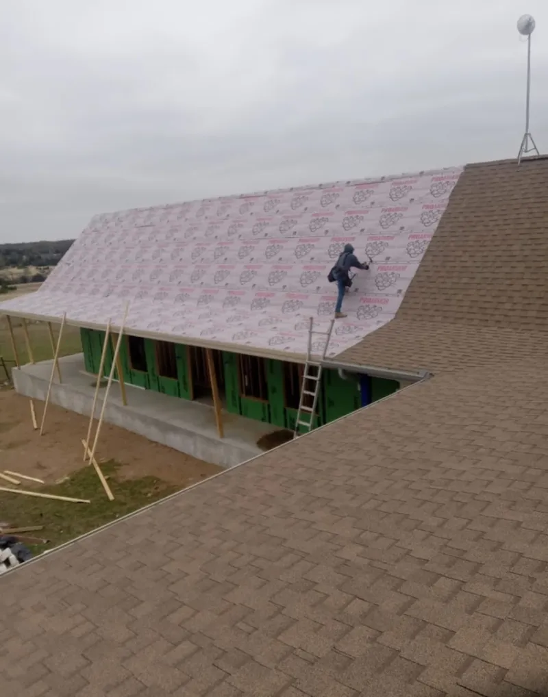 Worker preparing underlayment for a metal roof installation in Scaggsville